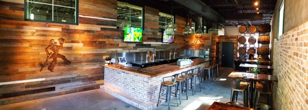 long bar with wood panel wall behind it with brewery logo